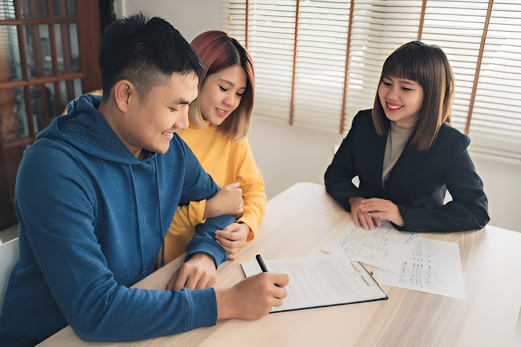 A couple signing a document while a loan officer watches.