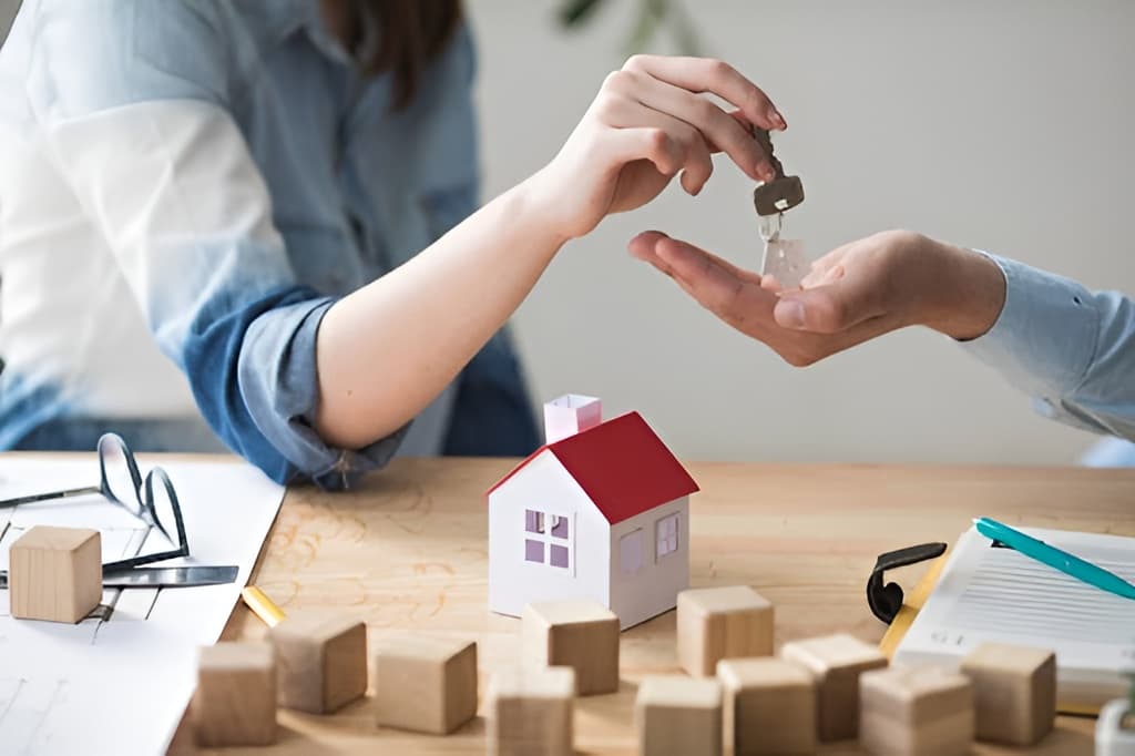 A person handing house keys to another person.